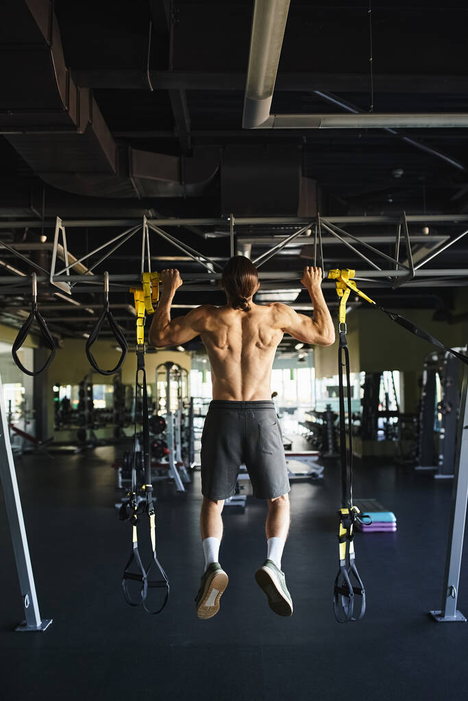 М'язистий чоловік без сорочки робить підтягування на барі в спортзалі. - Фото, зображення