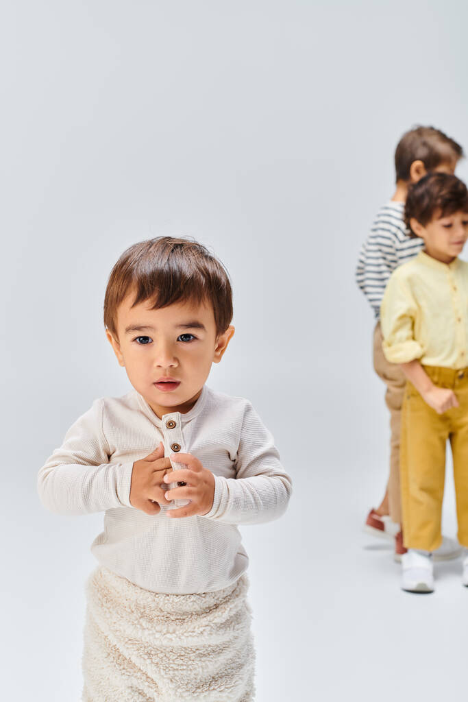 Ένα νεαρό αγόρι με περιέργεια λάμπει στα μάτια του στέκεται με αυτοπεποίθηση μπροστά σε ένα καθαρό λευκό φόντο. - Φωτογραφία, εικόνα