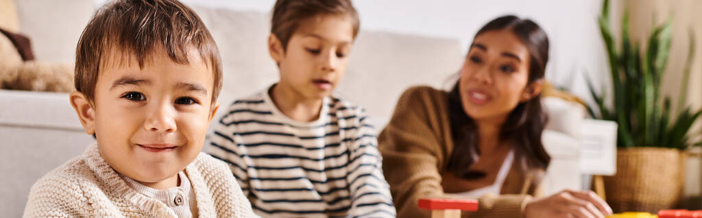 Jeune mère asiatique et ses petits fils aiment jouer avec des blocs colorés dans leur salon confortable. - Photo, image