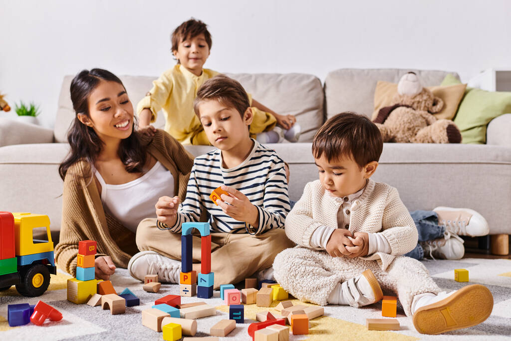 Un groupe d'enfants, guidés par leur jeune mère asiatique, jouent avec enthousiasme, empilent des blocs et s'immergent dans un jeu imaginatif. - Photo, image