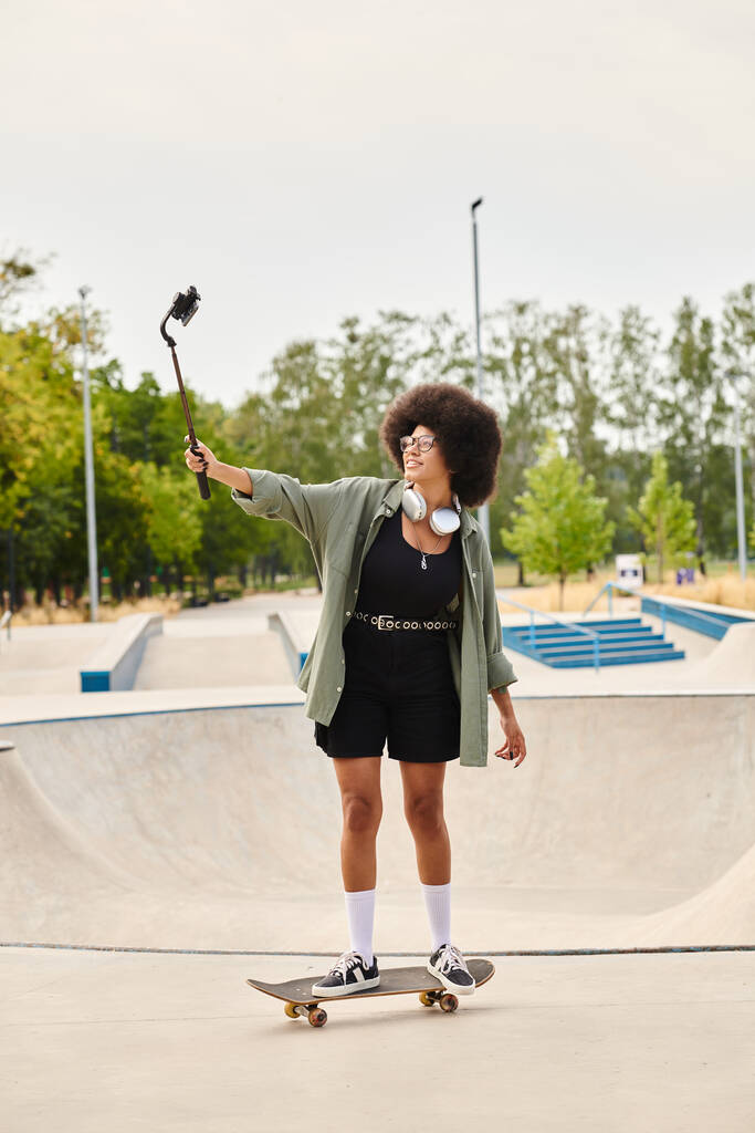 Afroamerikanerin mit lockigem Haar steht selbstbewusst auf einem Skateboard in einem lebhaften Skatepark. - Foto, Bild