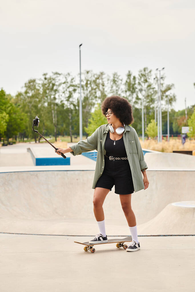 Una joven afroamericana con el pelo rizado monta con confianza en un monopatín en un bullicioso parque de skate. - Foto, imagen