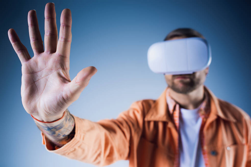 Een man in een studio beleeft de virtuele realiteit via een headset, ondergedompeld in de digitale wereld van het Metaverse. - Foto, afbeelding