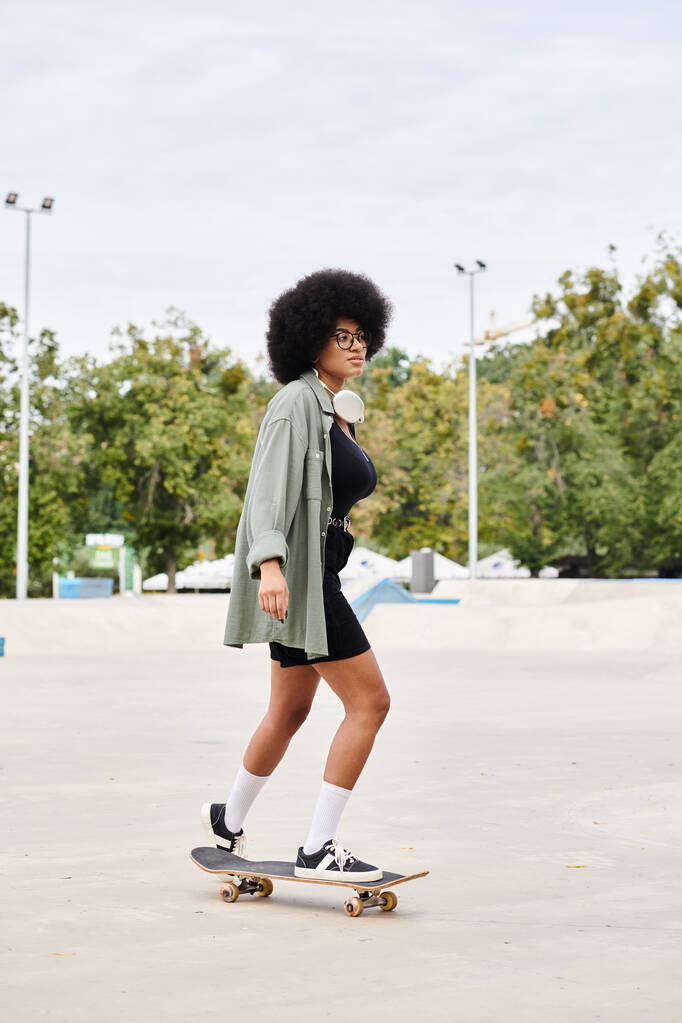 Uma jovem afro-americana com cabelo encaracolado monta sem esforço um skate em um estacionamento movimentado. - Foto, Imagem