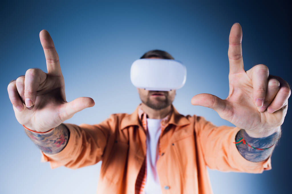 Um homem em um fone de ouvido VR, com os olhos vendados com uma faixa de cabeça, confiantemente faz com que o Vulcano assine em um estúdio. - Foto, Imagem