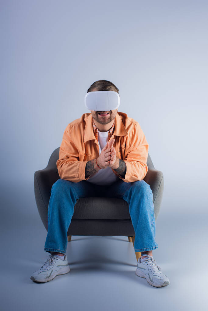Een man in een stoel in een blinddoek, verdwaald in de virtuele wereld met een VR-headset, in een studio. - Foto, afbeelding