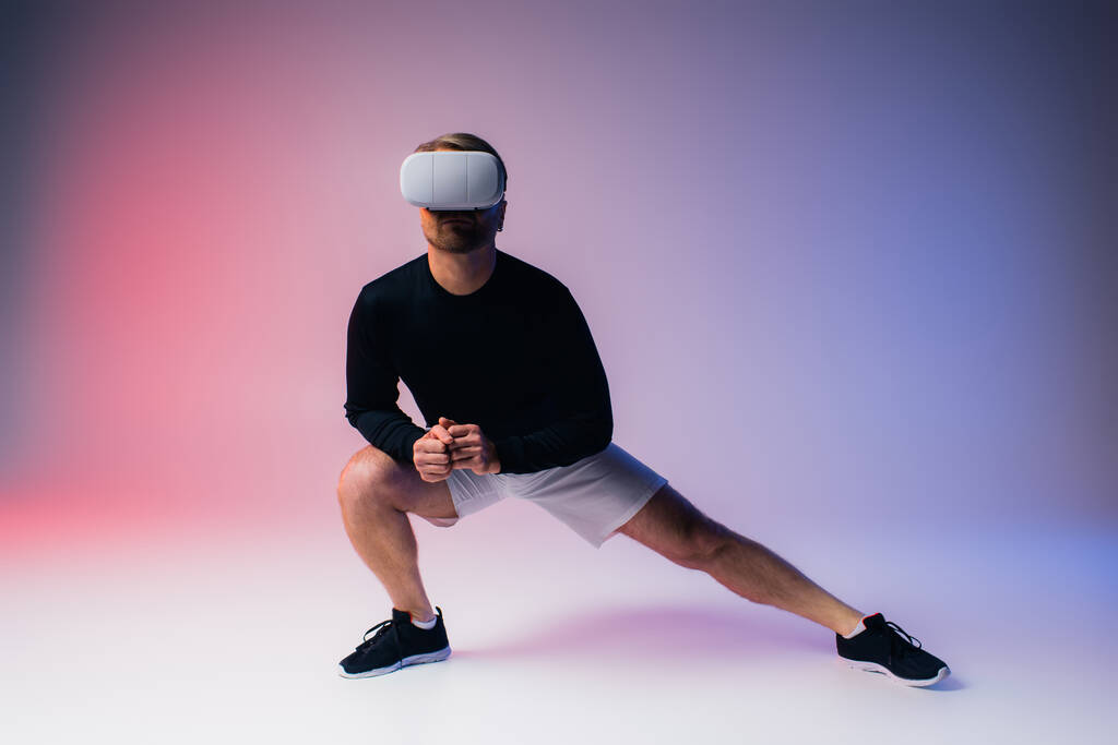 Egy fekete inges, fehér rövidnadrágos férfi magabiztosan áll egy stúdióban, VR headsetet viselve, átölelve a digitális világot.. - Fotó, kép