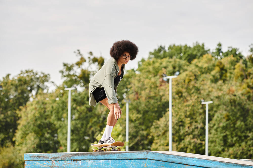 Молода афроамериканка з кучерявим волоссям витончено їде на скейтборді на пандусі у відкритому скейт-парку. - Фото, зображення