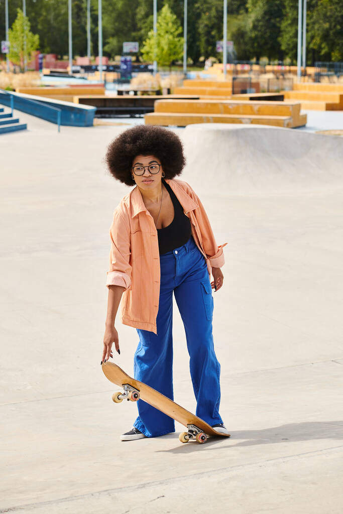 Giovane donna afroamericana si erge con fiducia su uno skateboard in un vivace skate park, mettendo in mostra le sue abilità e stile. - Foto, immagini