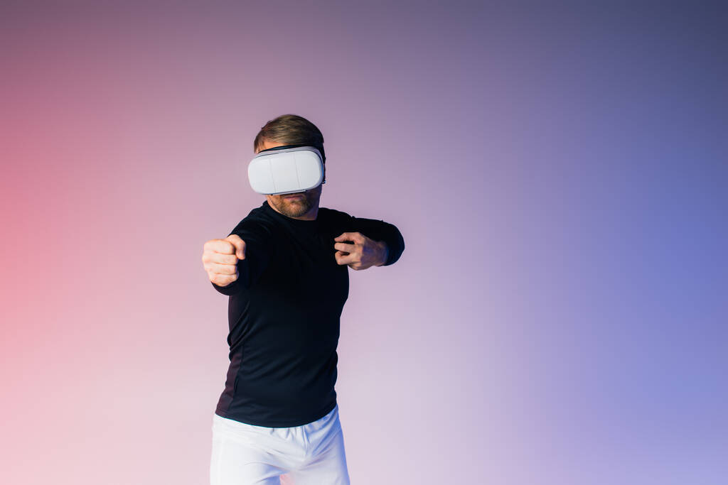 A man, blindfolded, stands before a vibrant pink and blue background in a surreal studio setting. - Photo, Image