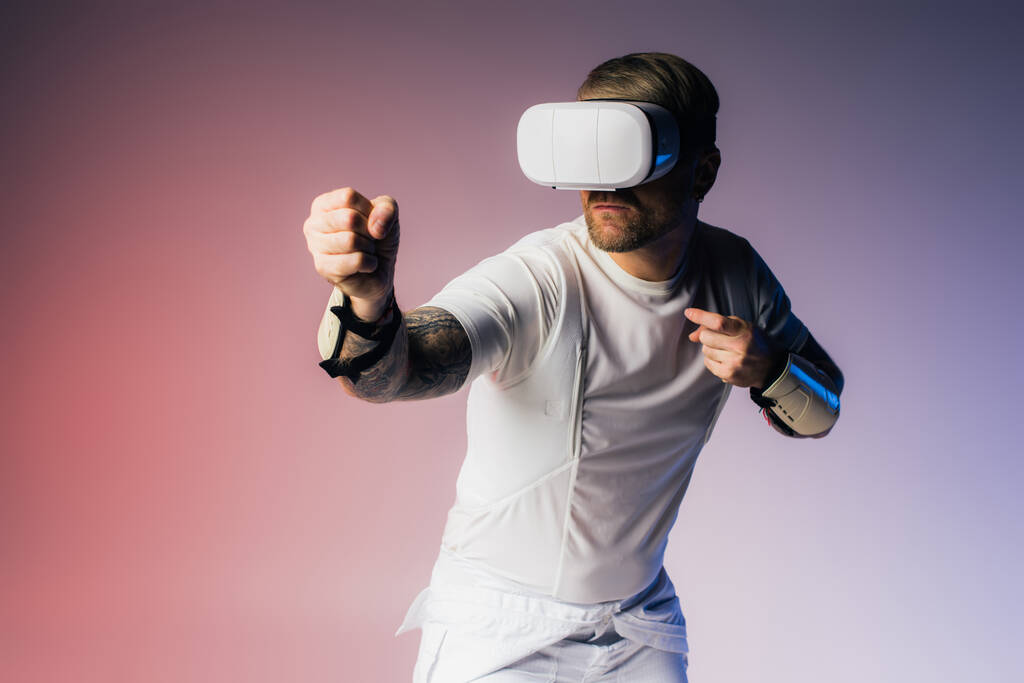 Un hombre con una camisa blanca explora el Metaverse a través de un auricular VR blanco en un entorno de estudio. - Foto, Imagen