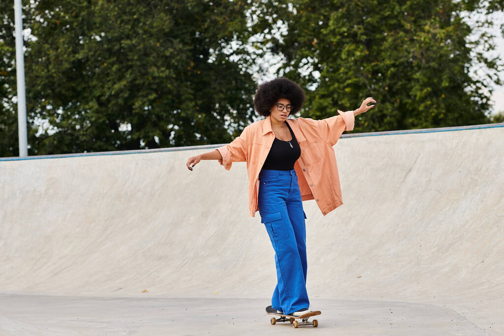 Молода афроамериканка з кучерявим волоссям впевнено їде на скейтборді в яскравому скейт-парку. - Фото, зображення