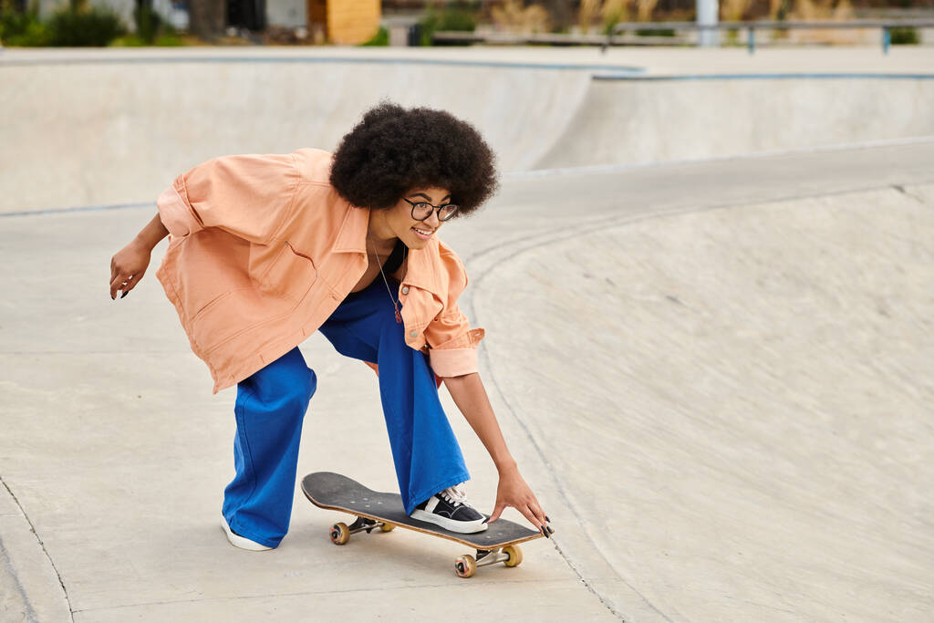 Eine junge Afroamerikanerin mit lockigem Haar skateboardet in einem lebhaften Skatepark und zeigt ihr Können auf dem Skateboard. - Foto, Bild