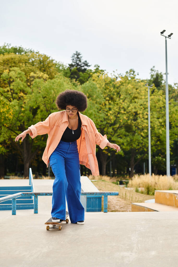 Afroamerykanka z kręconymi włosami pewnie jeździ na deskorolce na betonowej płycie w skateparku. - Zdjęcie, obraz