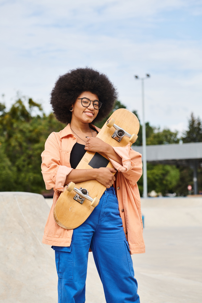 Una giovane donna afro-americana con capelli in stile afro sapientemente bilanciati su uno skateboard in uno skate park all'aperto. - Foto, immagini