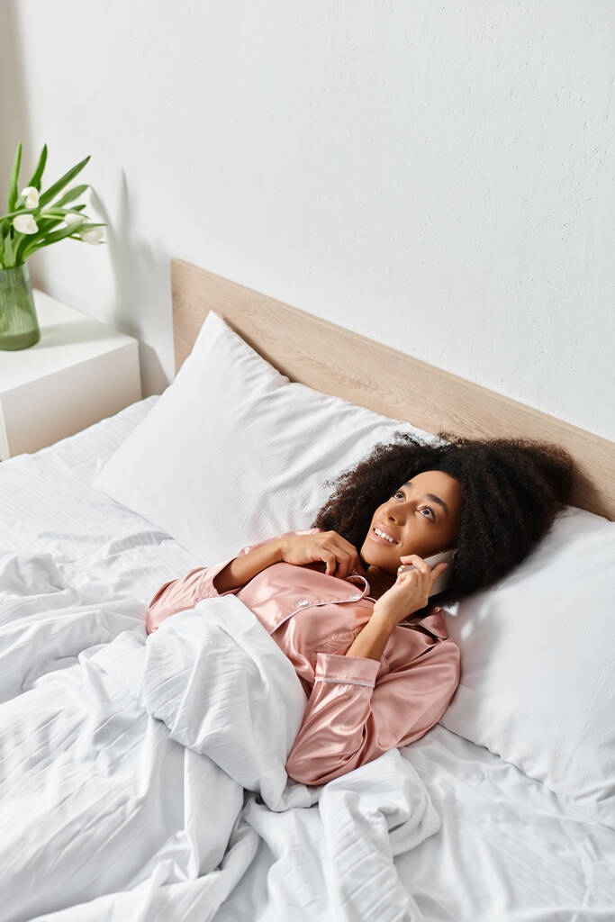 Una muñeca descansa pacíficamente en una cama perfectamente hecha con sábanas blancas, agregando un toque de fantasía al acogedor entorno del dormitorio.. - Foto, Imagen