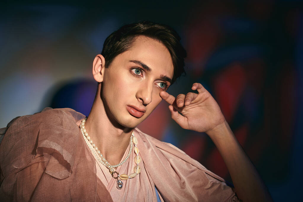chic sophisticated androgynous man in pastel elegant clothes looking away on vibrant backdrop - Photo, Image