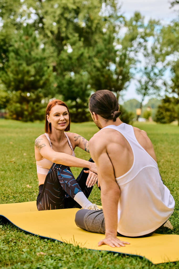 Een vrouw in sportkleding op een mat, begeleid door een personal trainer, toont vastberadenheid en motivatie. - Foto, afbeelding