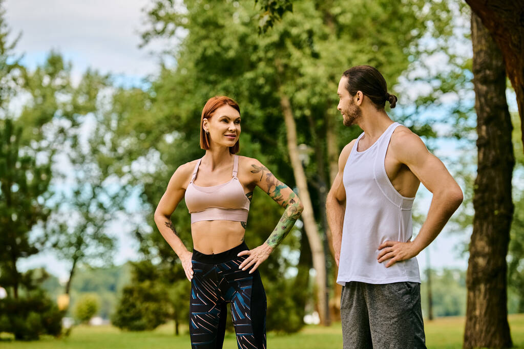 A determined woman in sportswear, working out with a personal trainer in a park. - Photo, Image