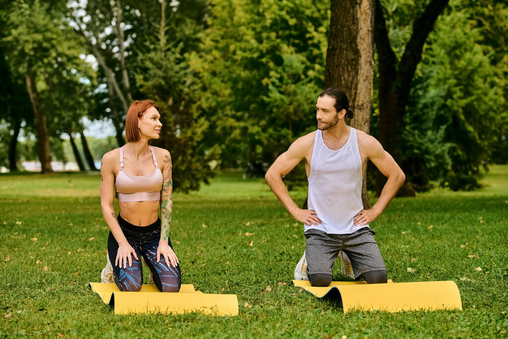Egy határozott férfi és nő a sportruházatban ül a fűben, egy személyi edző vezetésével egy edzésen.. - Fotó, kép