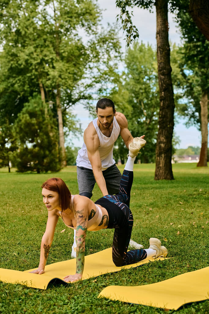 Una mujer en ropa deportiva practica yoga juntos en un parque con entrenador personal, mostrando determinación y motivación. - Foto, imagen