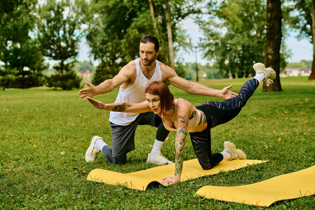 Een vrouw in sportkleding oefent buiten yoga met vastberadenheid en motivatie, begeleid door een personal trainer. - Foto, afbeelding