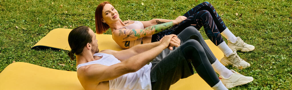 Een man en vrouw, gekleed in sportkleding, doen verschillende oefeningen op een felgele mat buiten. - Foto, afbeelding