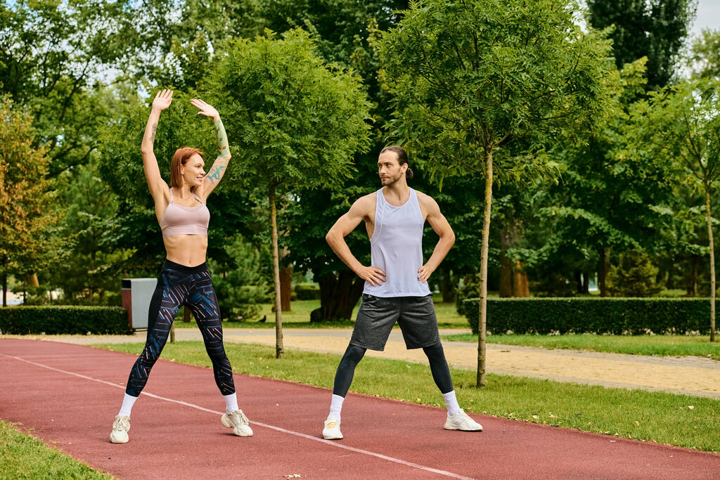 Решительный мужчина и женщина в спортивной одежде, тренируются вместе на треке, демонстрируют мотивацию и командную работу. - Фото, изображение
