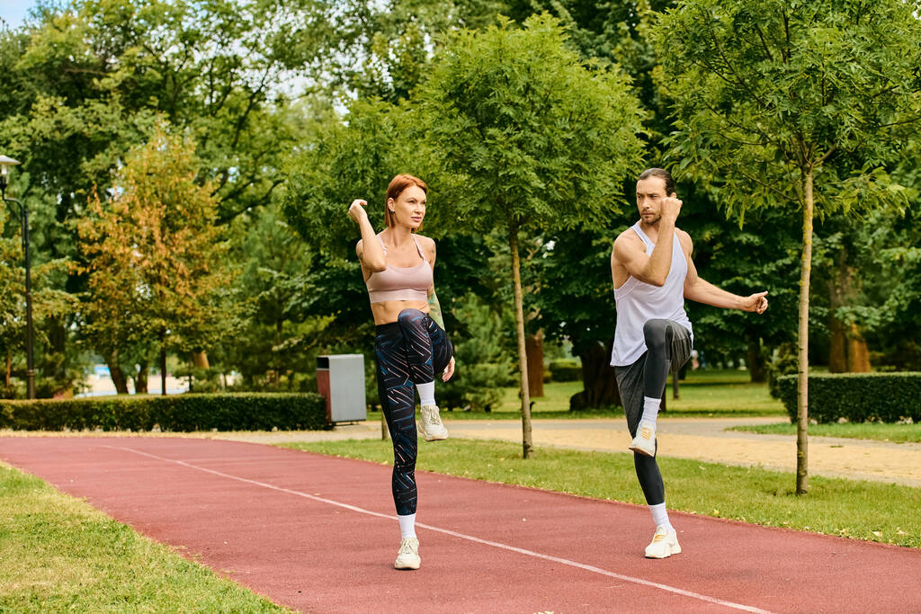 Решительный мужчина и женщина, одетые в спортивную одежду, растягиваются вместе на треке - Фото, изображение