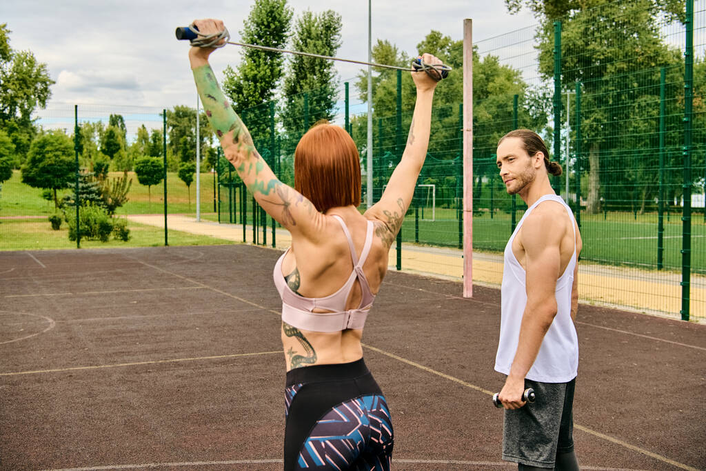 Een man en een vrouw in sportkleding staan op een veld, klaar om te oefenen onder leiding van hun persoonlijke trainer. - Foto, afbeelding