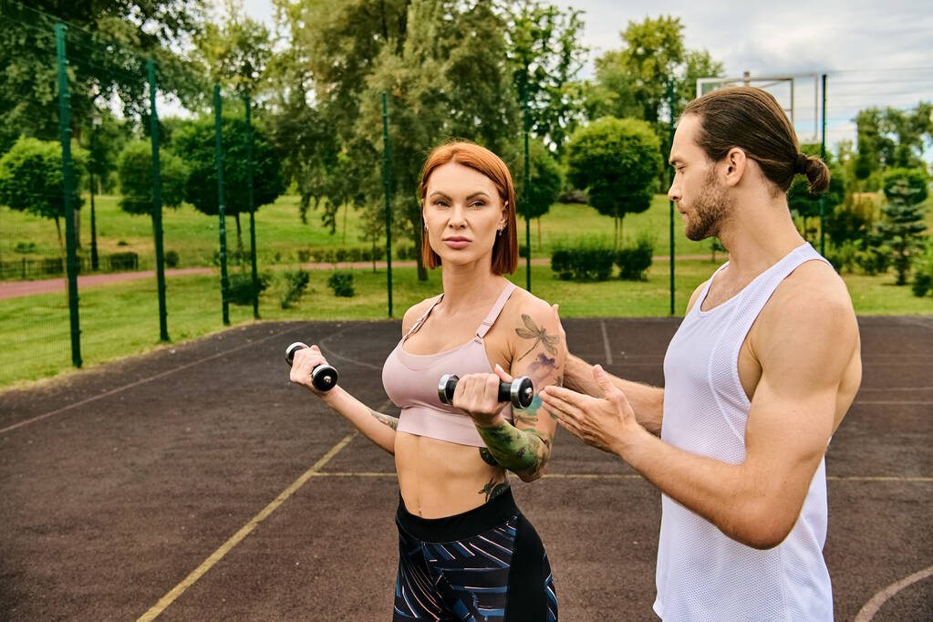 Um homem e uma mulher determinados no sportswear exercitando junto com halteres fora - Foto, Imagem