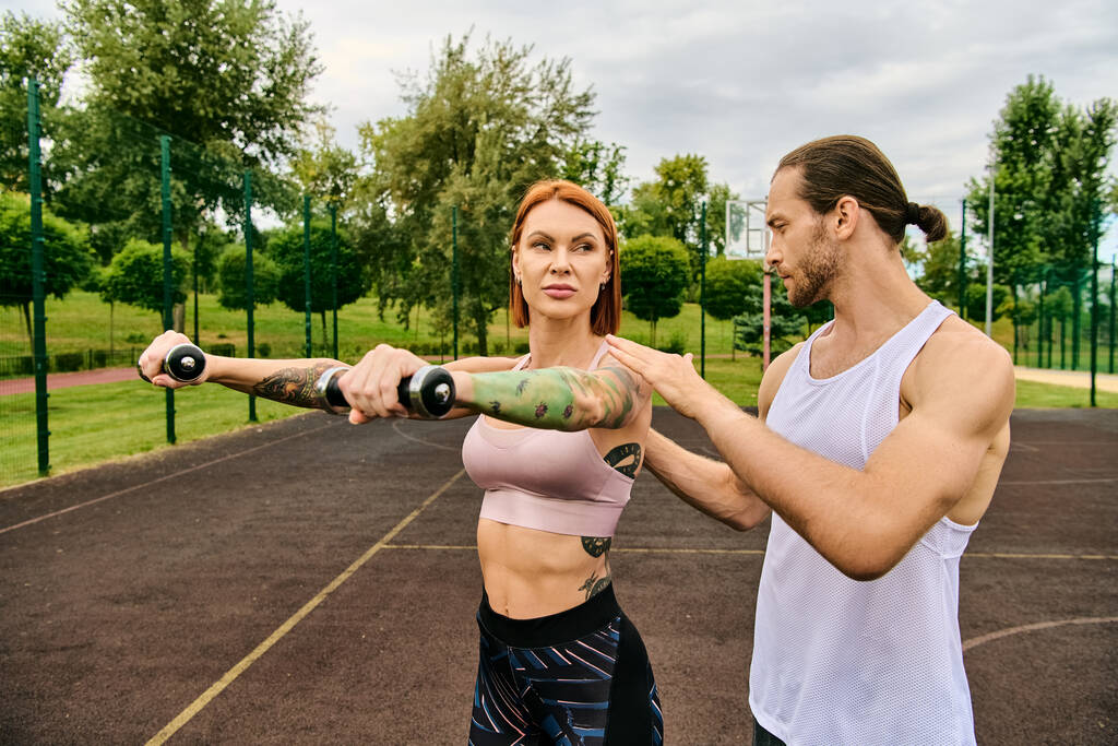 Un hombre y una mujer decididos en ropa deportiva haciendo ejercicio con pesas - Foto, imagen