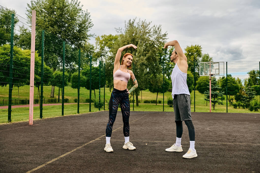 Um homem e uma mulher em sportswear estão em cima de uma quadra de basquete, mostrando sua determinação e motivação enquanto exercem - Foto, Imagem