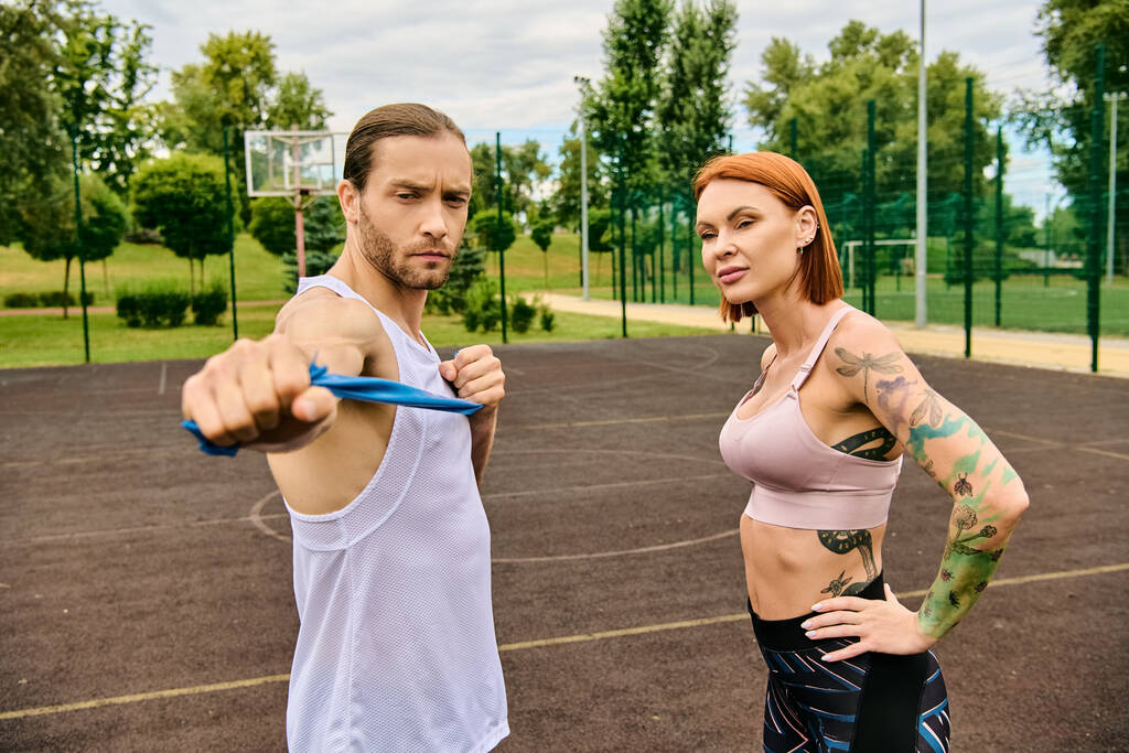 Un hombre y una mujer en ropa deportiva están de pie con confianza en una cancha, mostrando determinación y motivación. - Foto, imagen