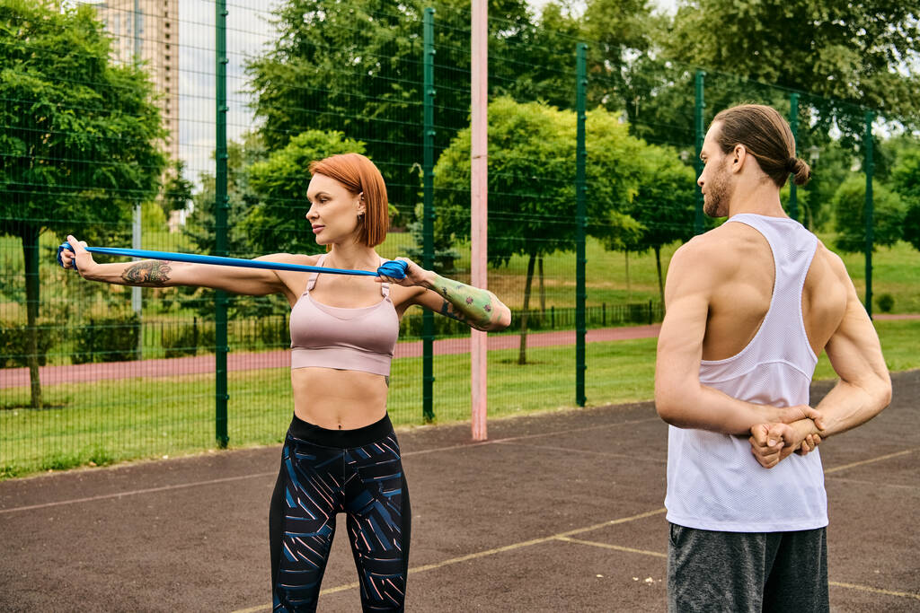 Een vrouw in sportkleding, begeleid door een personal trainer, die hartstochtelijk traint op een veld, toont vastberadenheid en motivatie. - Foto, afbeelding