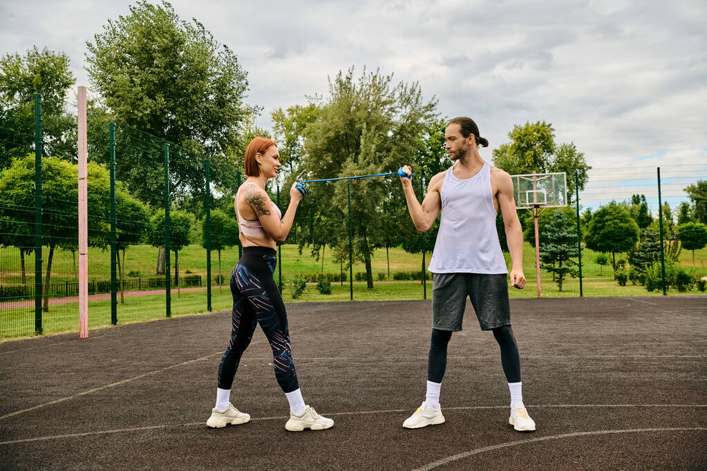 Ένας αφοσιωμένος προσωπικός γυμναστής και μια αποφασισμένη γυναίκα στα αθλητικά στέκονται αποφασιστικά στο γήπεδο, ενσαρκώνοντας κίνητρο.. - Φωτογραφία, εικόνα