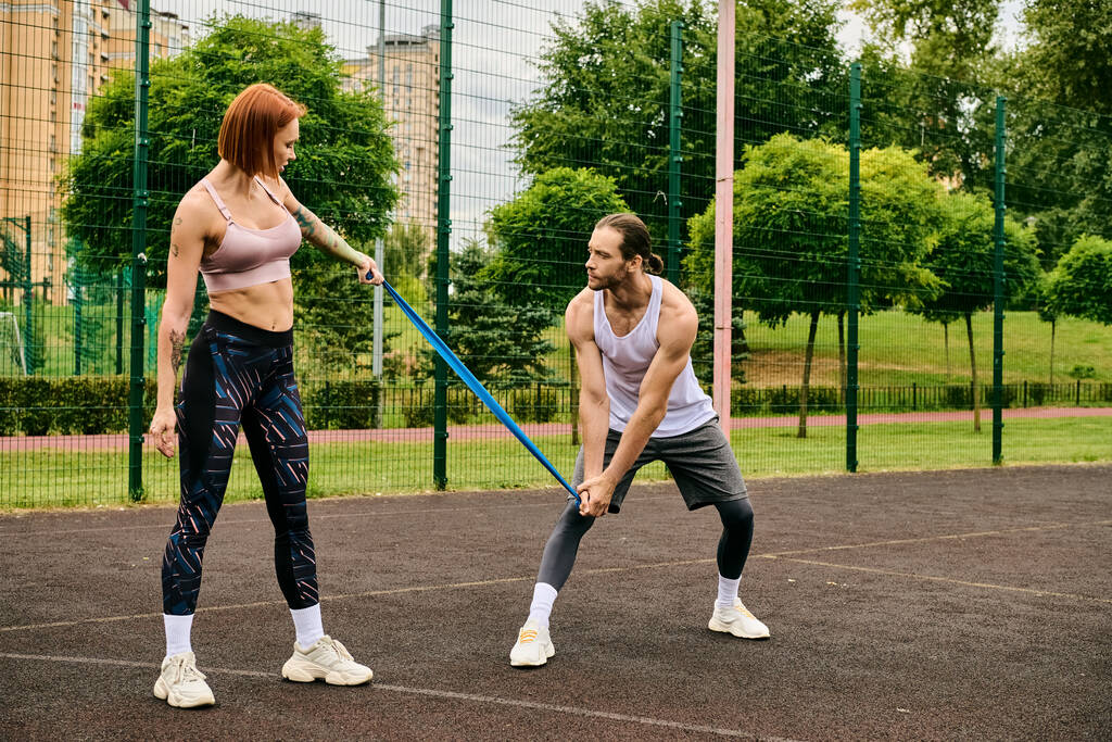 Zdeterminowany mężczyzna i kobieta w odzieży sportowej stoją na korcie tenisowym, koncentrując się na ich rutynowych ćwiczeń. - Zdjęcie, obraz