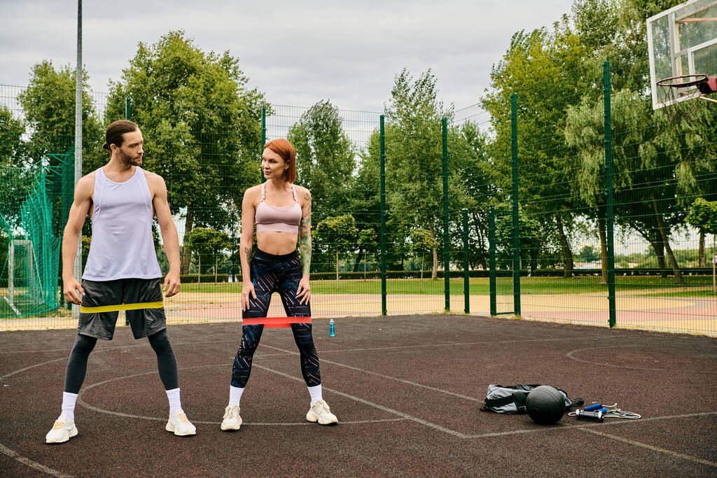 Egy férfi és egy nő a sportruházatban, akik ellenállássávos kiképzésen vesznek részt, eltökéltséget és motivációt mutatnak. - Fotó, kép