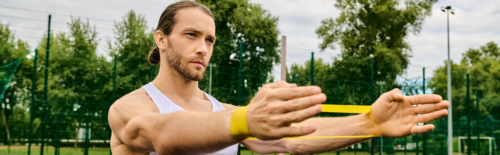 Um homem segura um objeto amarelo vibrante em suas mãos, treinamento de banda de resistência - Foto, Imagem