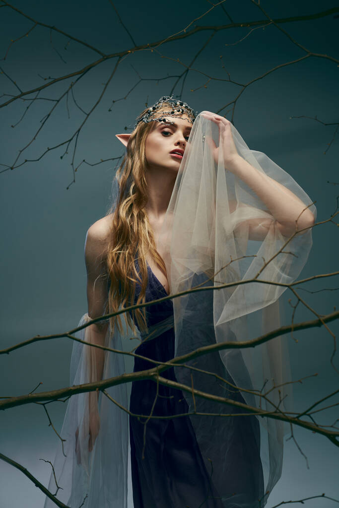 Een jonge vrouw in een jurk die op een elfenprinses lijkt, versierd met een sluier, ademt een sfeer van fantasie en betovering uit in een studio.. - Foto, afbeelding
