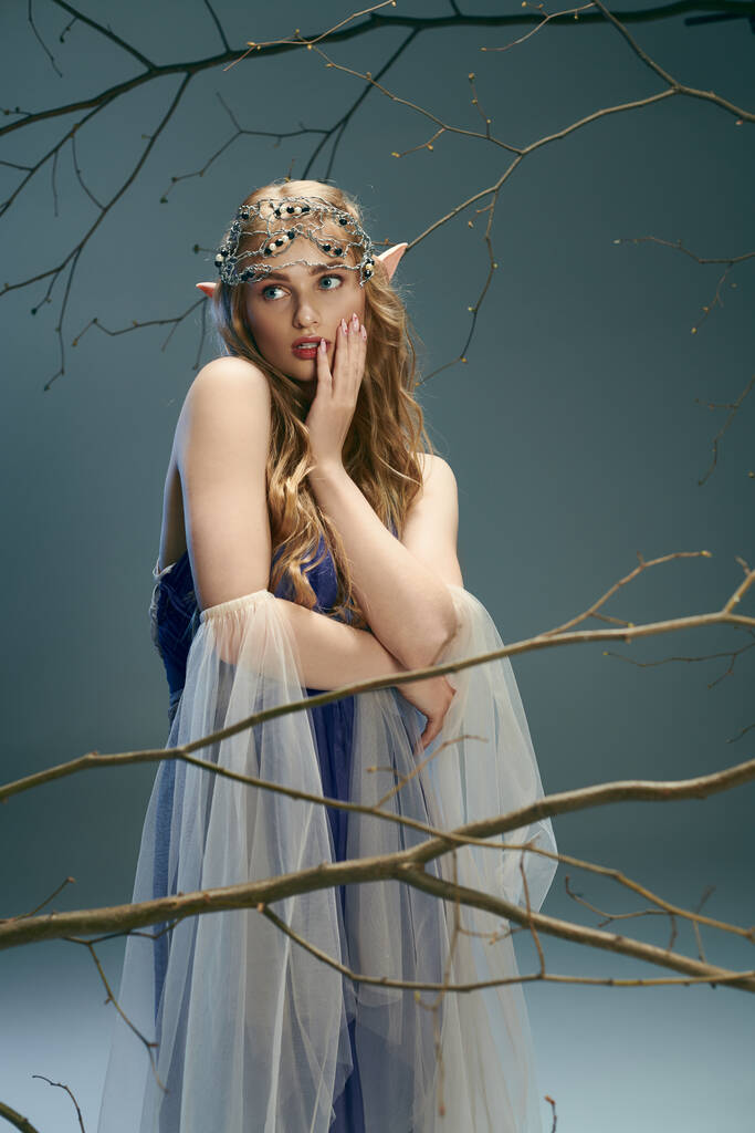 Μια νεαρή γυναίκα, που μοιάζει με πριγκίπισσα ξωτικό, ποζάρει με μπλε φόρεμα σε ένα μαγικό σκηνικό στούντιο.. - Φωτογραφία, εικόνα