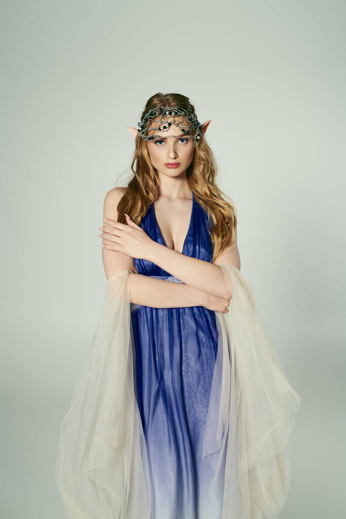 Una joven mujer exuda elegancia en un vestido azul con un delicado velo, encarnando la personalidad de una encantadora princesa elfa en un entorno de estudio. - Foto, imagen