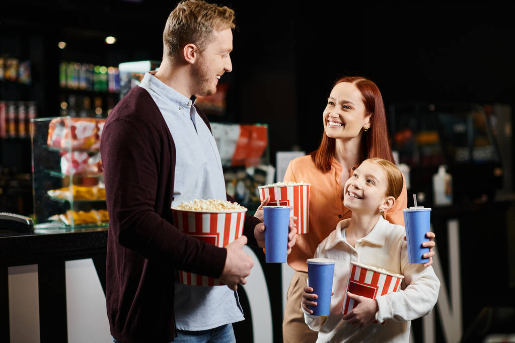 Una famiglia allegramente tiene popcorn mentre condivide un momento insieme. - Foto, immagini