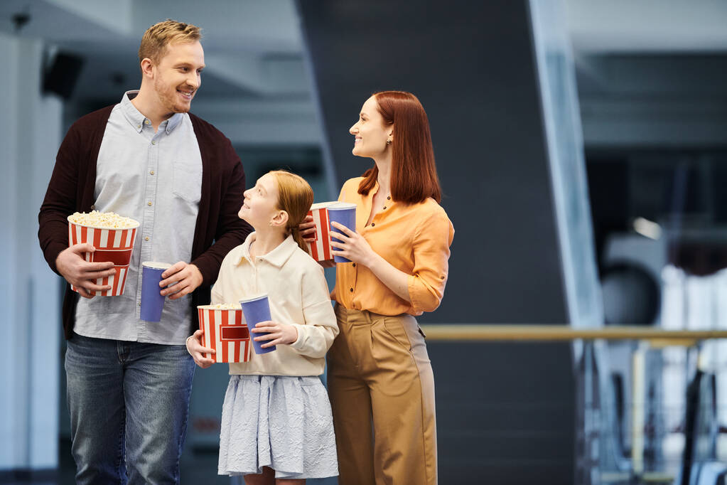 Una famiglia felice si trova in un cerchio, ognuno con una scatola di popcorn al cinema, godendo di una divertente serata cinematografica insieme. - Foto, immagini