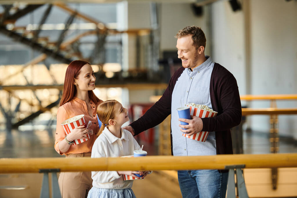 Ein fröhlicher Mann, eine Frau und ein Kind halten Popcorn im Kino. - Foto, Bild
