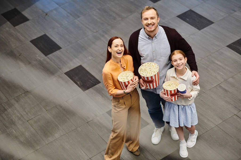 Ein Mann und seine Familie halten fröhlich Popcornboxen im Kino in der Hand und genießen einen gemeinsamen Familienfilmabend. - Foto, Bild
