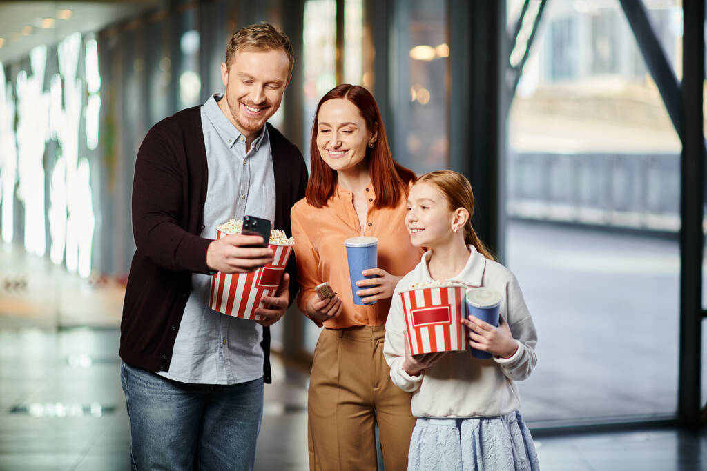 familia alegremente sosteniendo cajas de palomitas de maíz en el cine, uniéndose - Foto, imagen