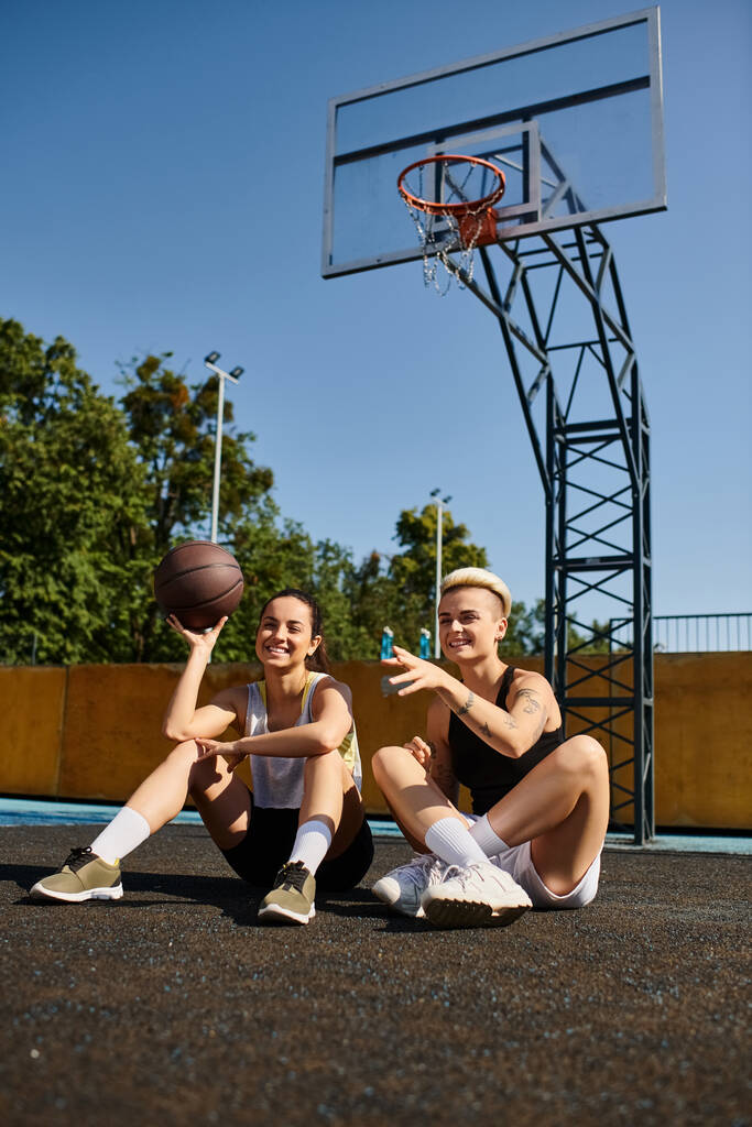 Due giovani donne godono di una partita di basket a terra sotto il sole estivo. - Foto, immagini