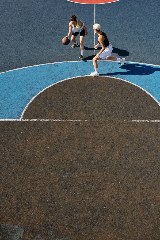 jeunes femmes jouant au basket sur un terrain extérieur, s'engageant dans un jeu compétitif et énergique. - Photo, image