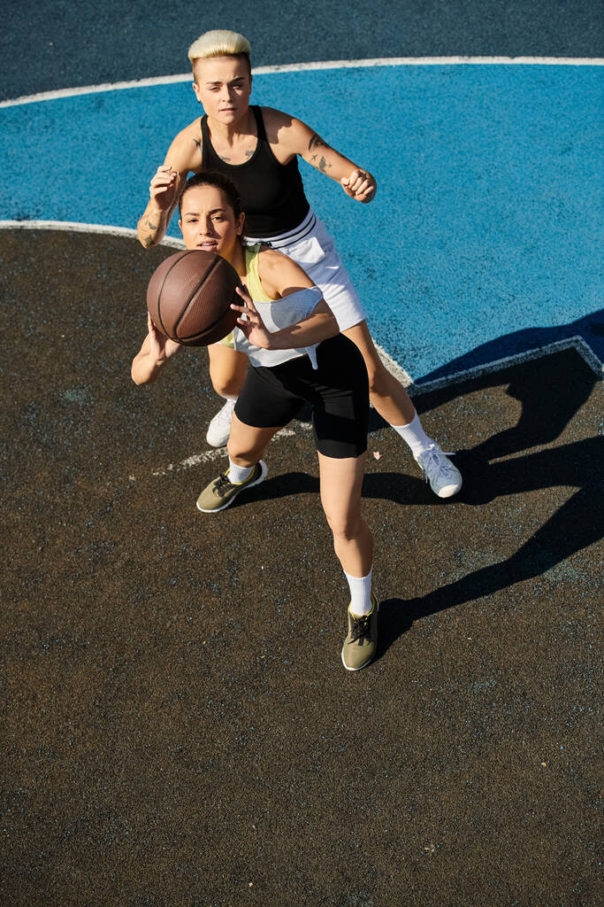 Dwie młode kobiety, wysportowane i konkurencyjne, angażujące się w przyjazną grę w koszykówkę pod letnim słońcem. - Zdjęcie, obraz